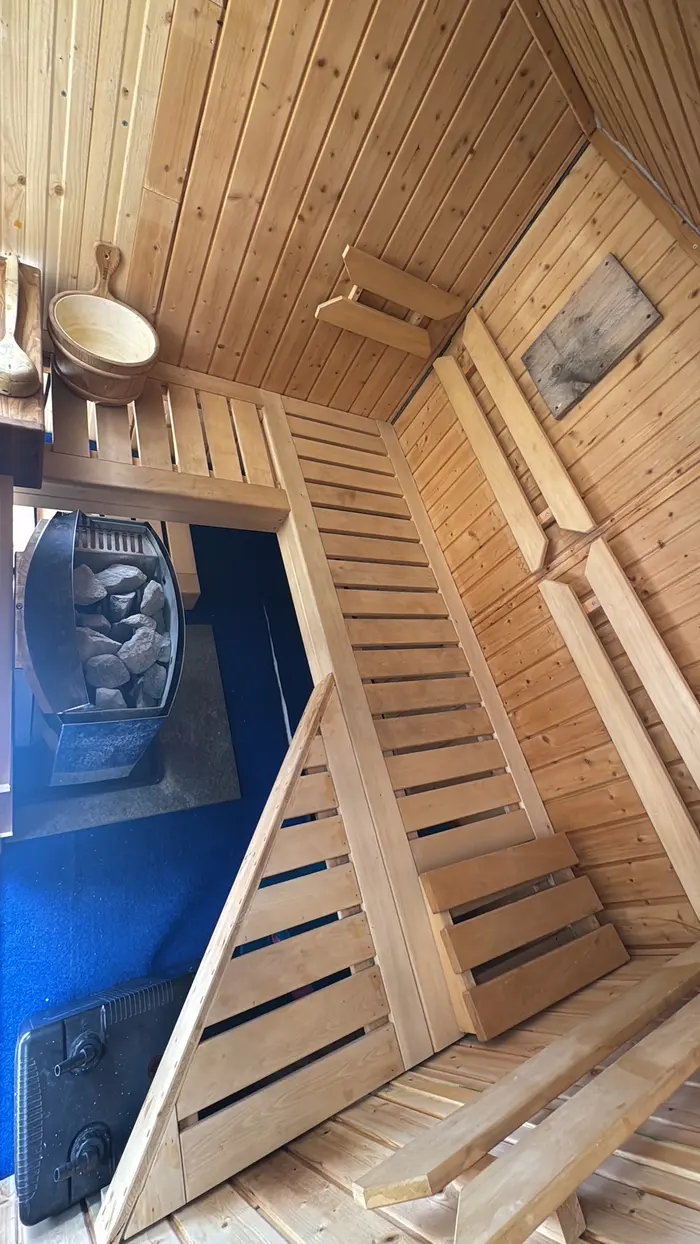 Sauna-Innenraum aus Holz mit Bänken und Saunaofen