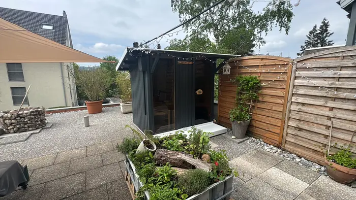 Gartensauna eingebettet in eine Terrasse mit Sichtschutz